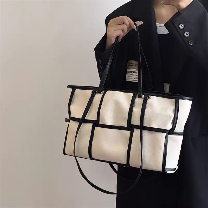 Side view of a black grid canvas tote bag showing the durable fabric texture and sturdy shoulder straps.
