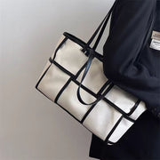 Close up side view of the Black Grid Canvas Tote Bag featuring a white windowpane pattern on durable black fabric.